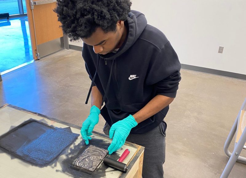 Student wearing gloves working on print.